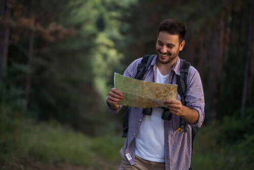 Happy man in the woods looking at a map
